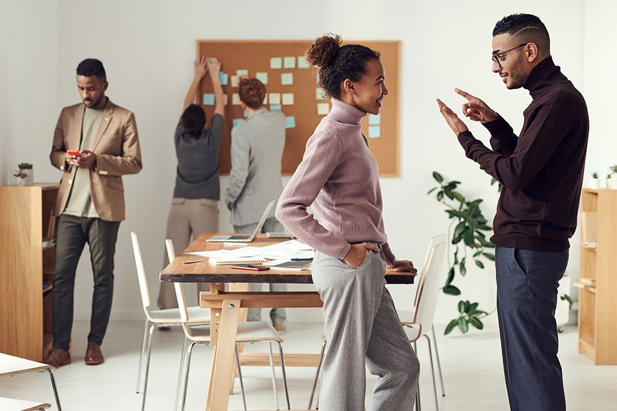 Colleagues engage in a lively discussion while others work in the background in a modern office. Colleagues engage in a lively discussion while others work in the background in a modern office.