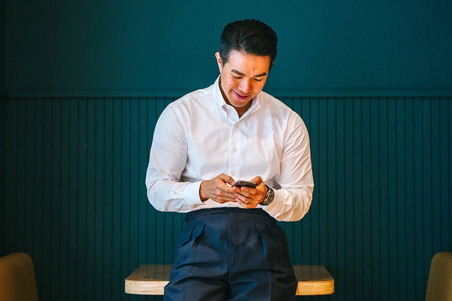 Man in white shirt smiling while using his phone indoors. Man in white shirt smiling while using his phone indoors.